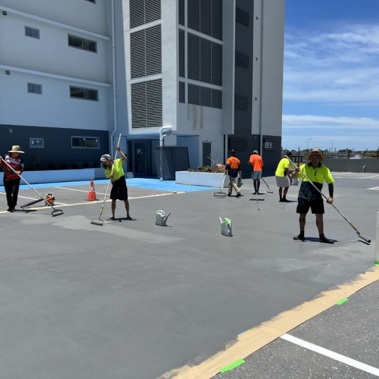 True Grit workers painting the surface of a parking lot.