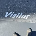 A person standing next to the word visitor on a finished epoxy floor.