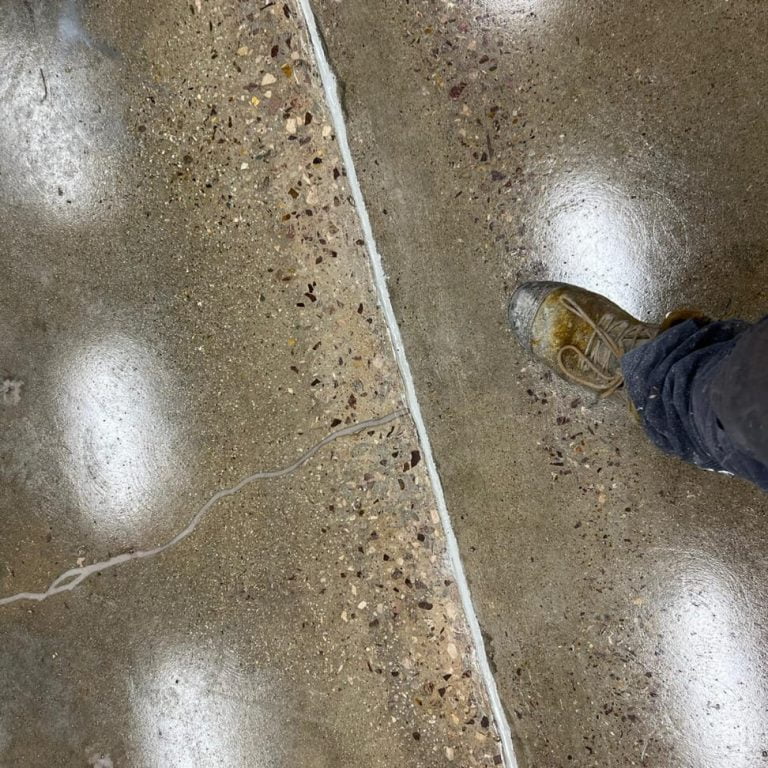 A person's feet standing on a restored concrete floor.