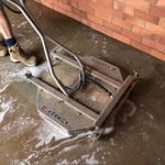 A man cleaning a concrete floor with a machine.