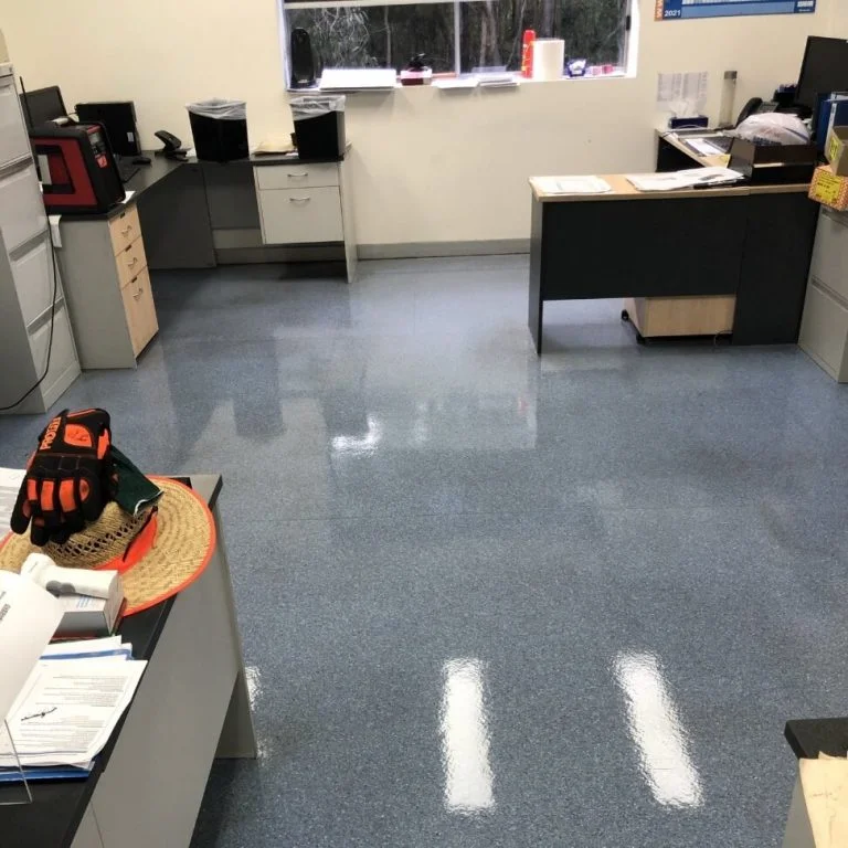 A clean office with blue epoxy flooring and desks.