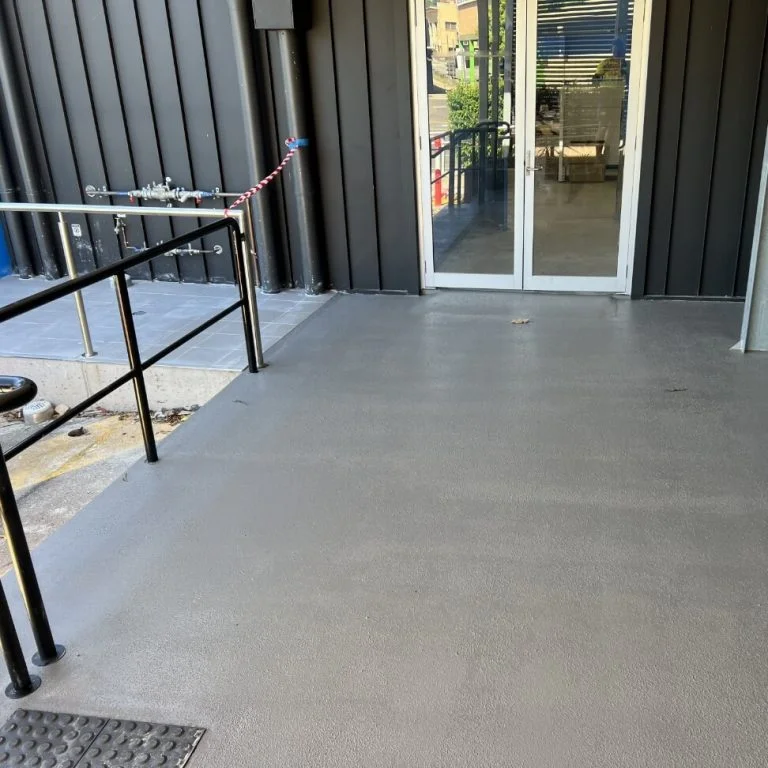 A restored concrete floor with a metal railing and a door.