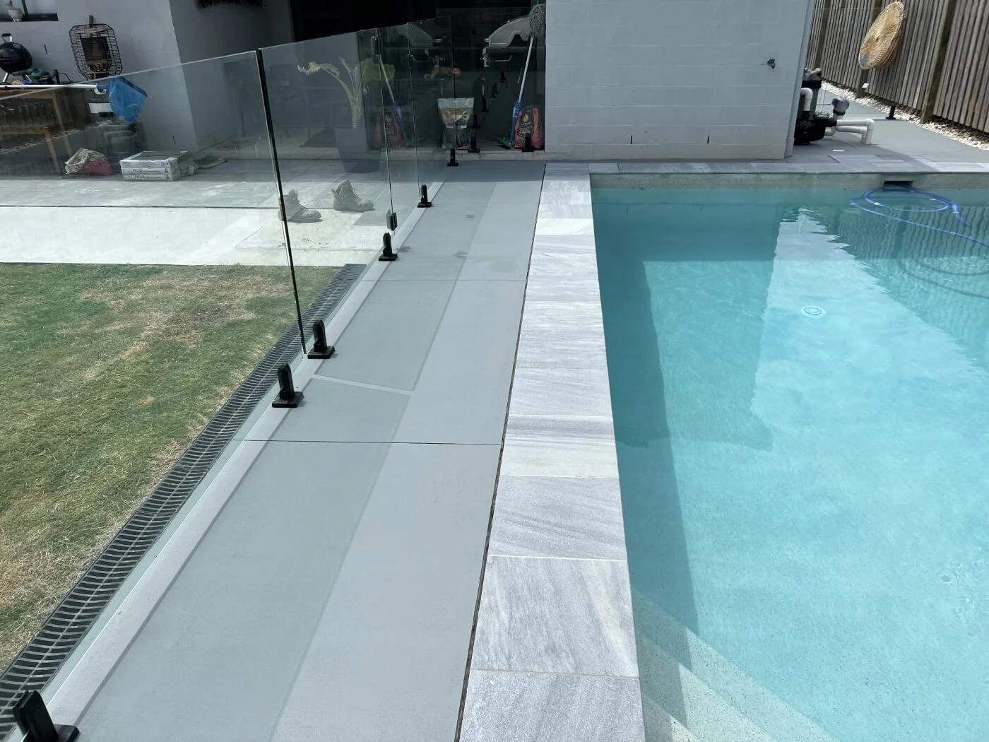 A swimming pool with a glass fence and sealed tyles.