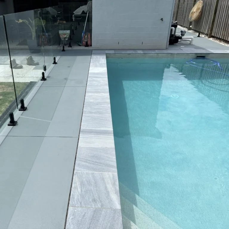 A swimming pool with a glass railing and waterproofed tyles