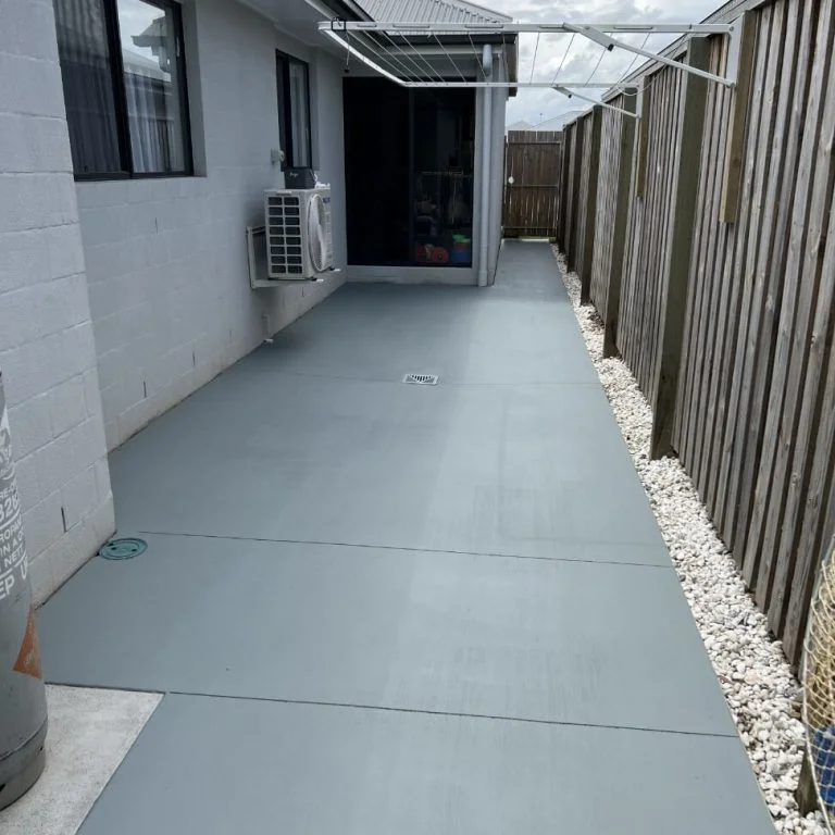 A restored concrete patio in a backyard with a fence.
