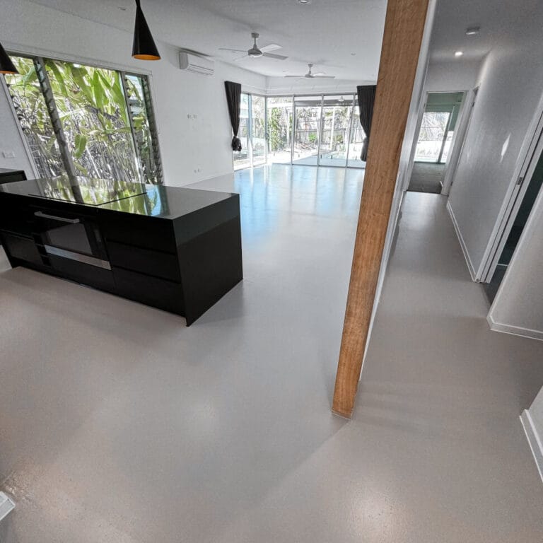 Modern open-plan kitchen and living area with large windows, black island counter, light flooring, and ceiling fans.