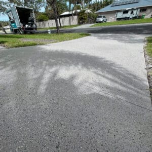 Driveway with tree shadow, parked van, and a house with a caravan in the background.