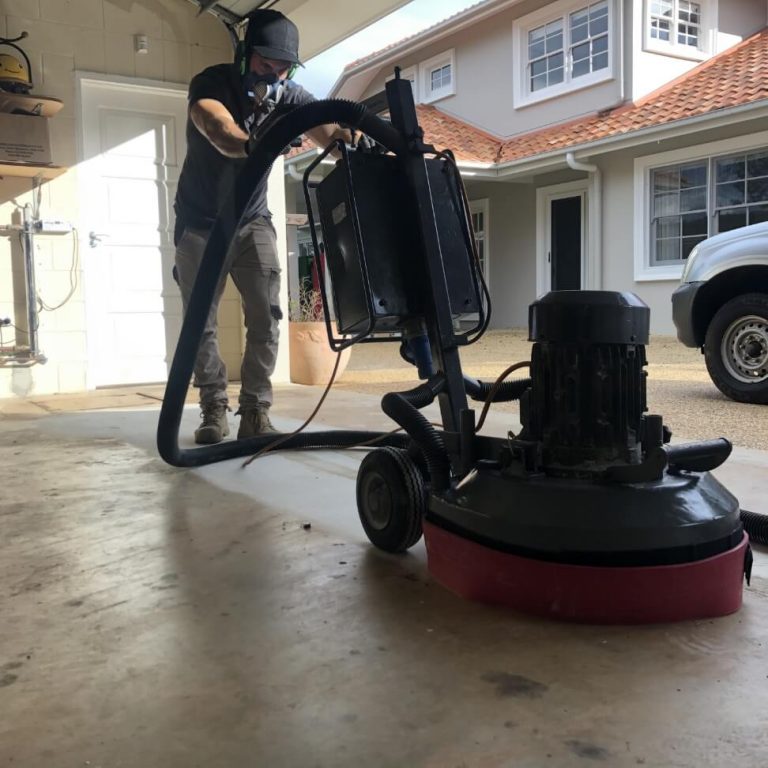 True Grit worker using a floor polisher in a garage.
