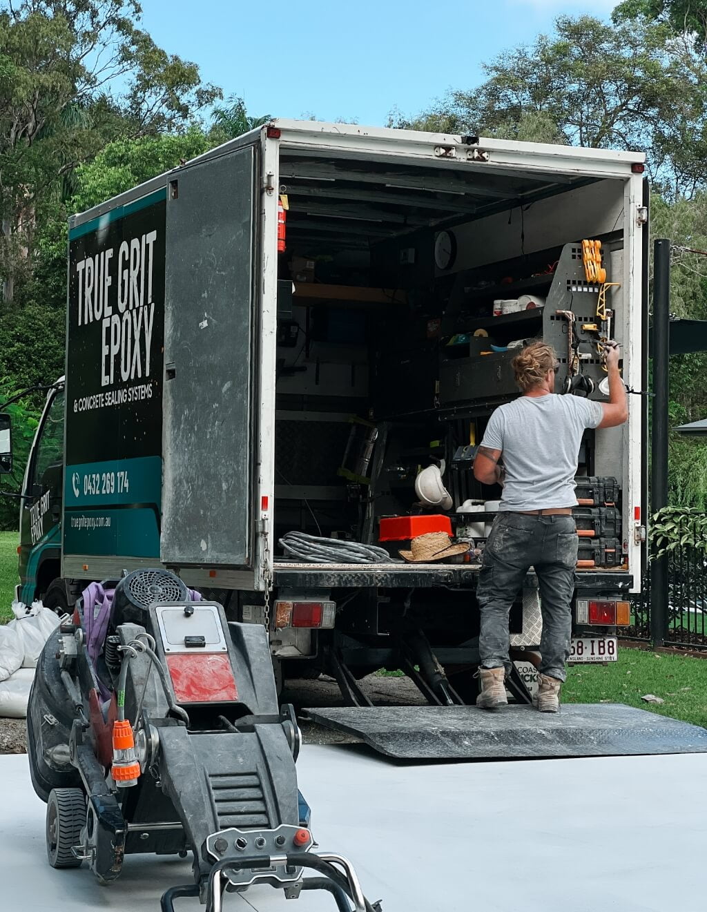 A man unloading a truck with epoxy flooring tools in it.