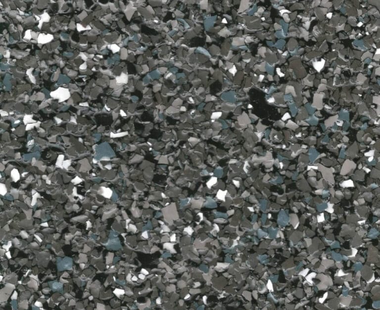 A close-up view of a textured surface with small, irregular, gray, white, and dark specks.