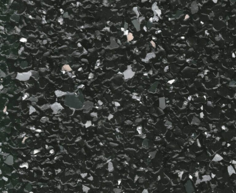 Close-up of a dark terrazzo surface with scattered light and dark gray chips, creating a speckled pattern.